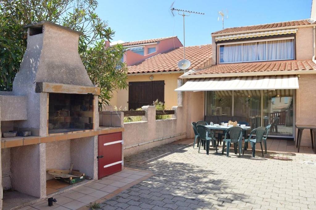une cuisine extérieure avec une table et des chaises et un bâtiment dans l'établissement SP330-028 Maison 5 pièces SAINT PIERRE LA MER, à Saint Pierre La Mer