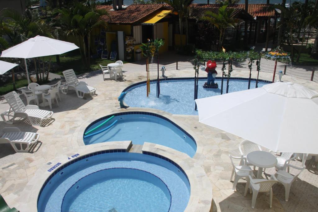 a swimming pool with chairs and tables and umbrellas at Pousada do Frances in Bertioga