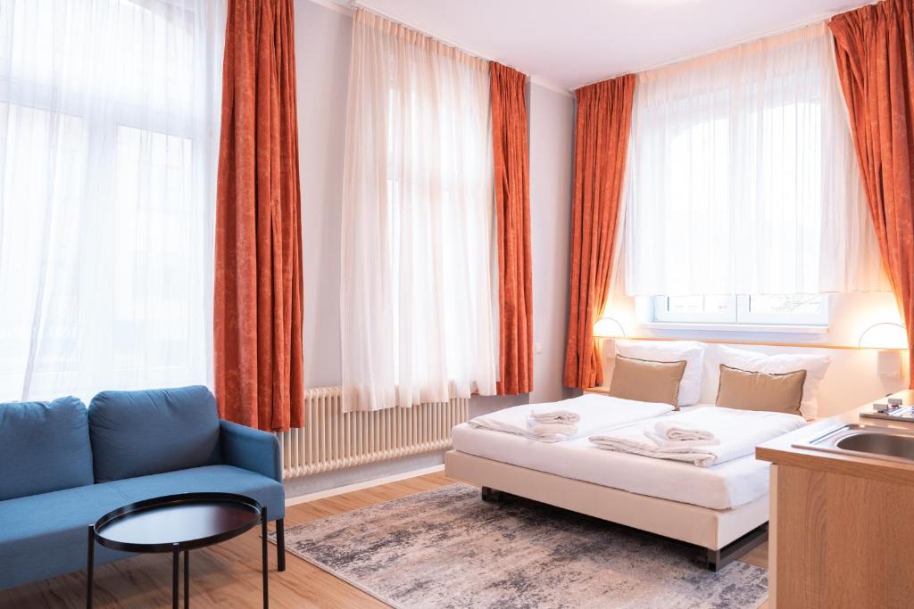 a living room with a white couch and a blue chair at UNEA Aparthotel in Leipzig - Vollausgestattete Apartments in Leipzig