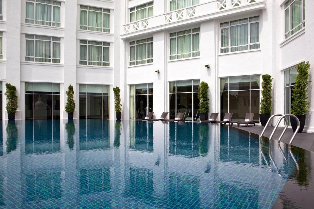 A tiled outdoor pool enclosed by the hotel’s white façade.