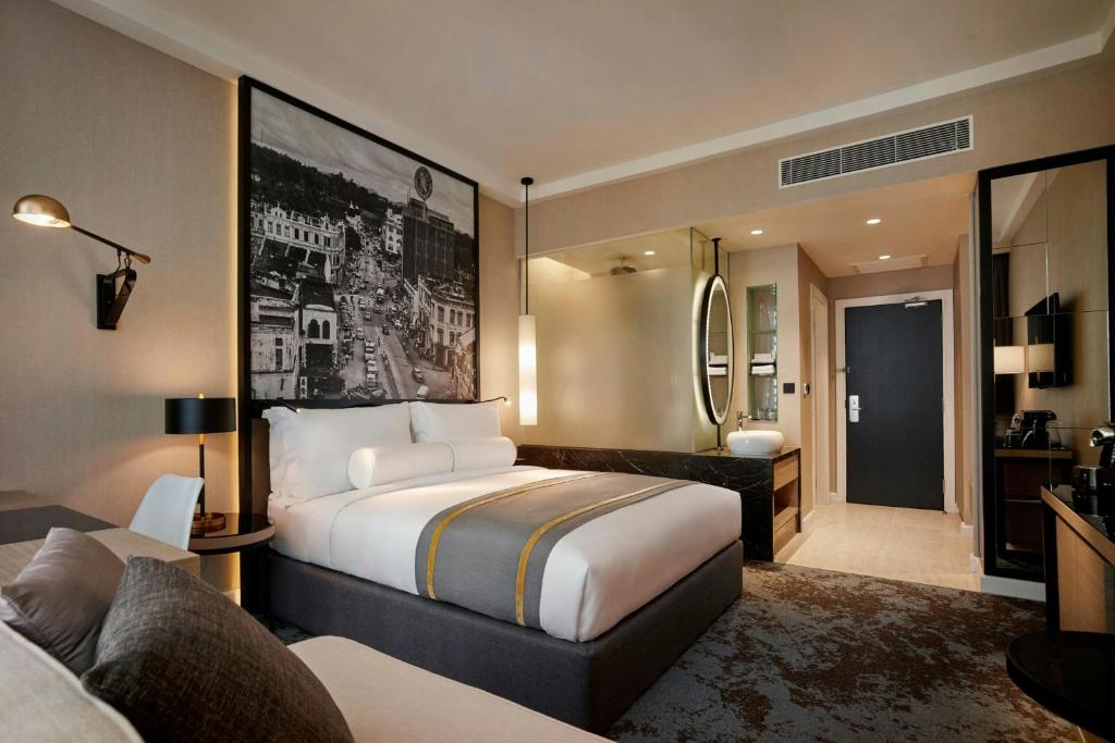 A contemporary guest room combines a king bed, sofa corner and open bathroom zone.