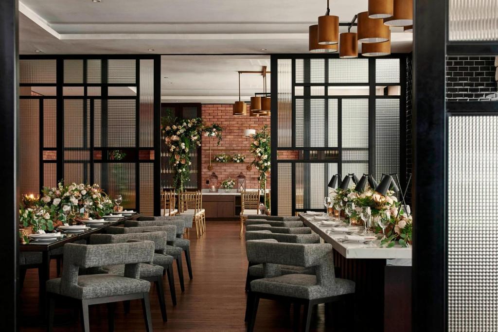 A formal restaurant dining room arranged with long tables and upholstered chairs.