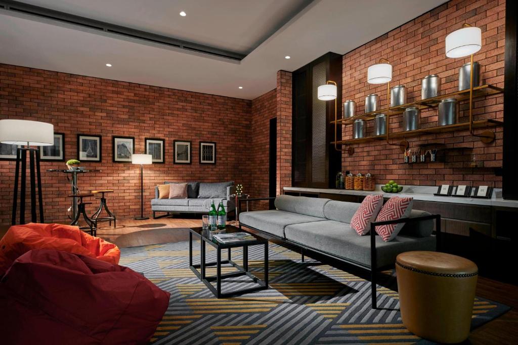 A brick-walled lounge with sofas, a coffee table and a small refreshment counter.