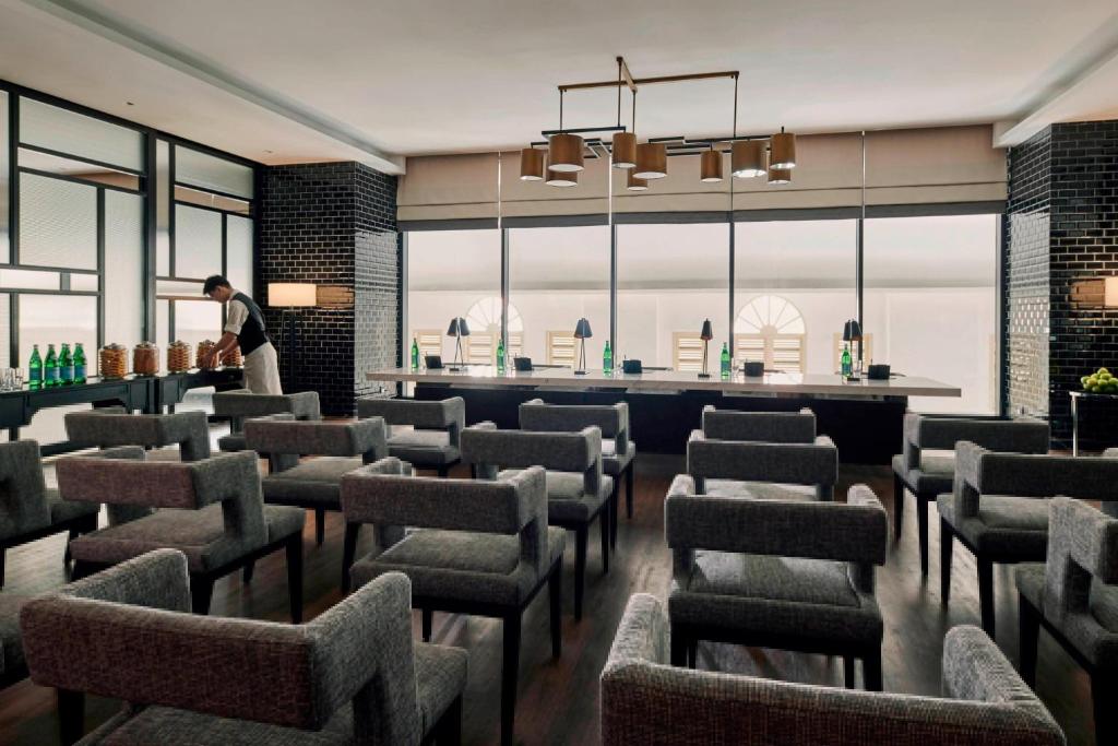 A bright waiting lounge lined with rows of upholstered chairs and a window-side counter.