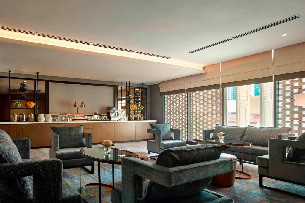 A spacious lounge with sofas, armchairs, a circular table and a bright patterned window wall.