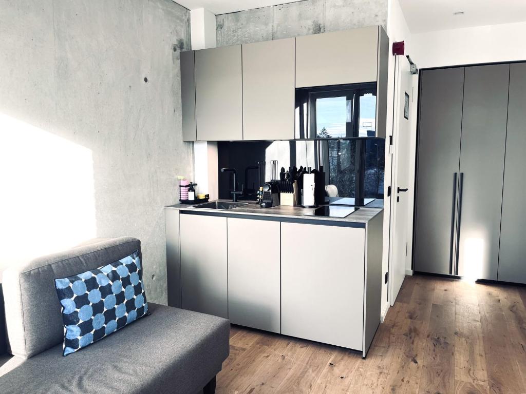 eine Küche mit weißen Schränken und einem Sofa in einem Zimmer in der Unterkunft Mikes Apartments Munich in München