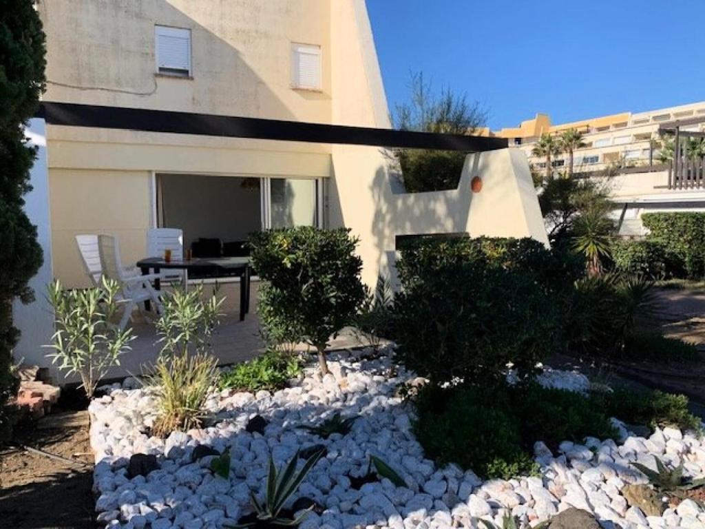 un jardin en face d'une maison avec des rochers dans l'établissement Résidence Port Nature Village 3 - Villa Duplex 6 Pers. Port Nature Village MAE-2884, au Cap d'Agde