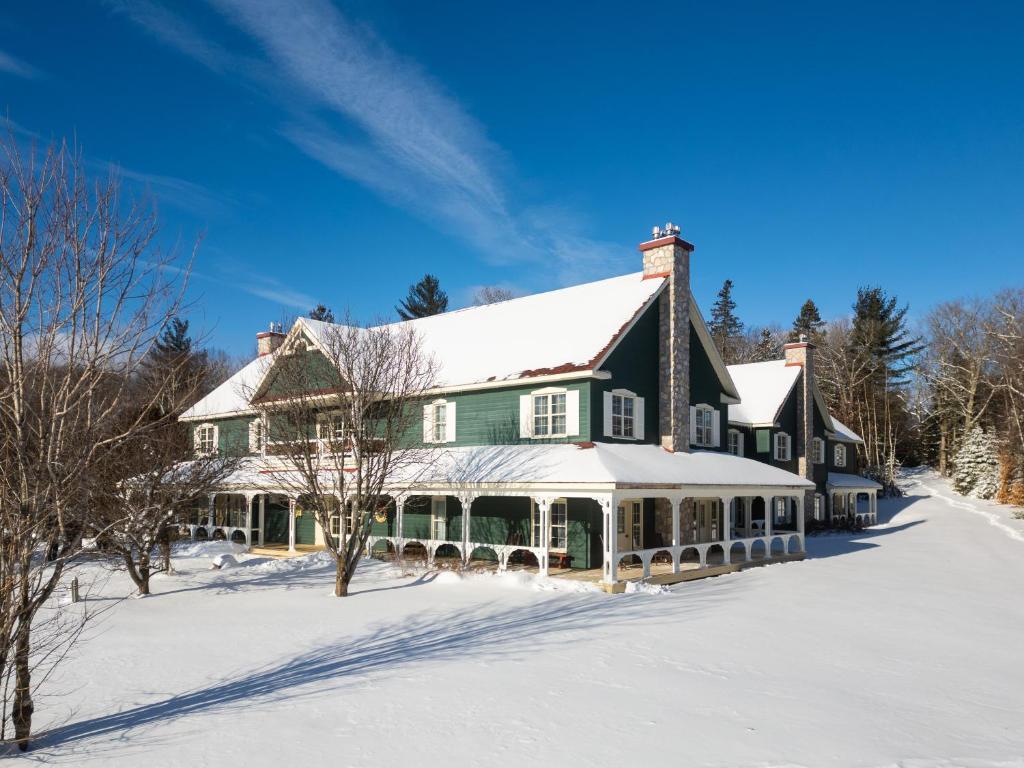 een groot groen huis met sneeuw op de grond bij Le Baluchon Éco-villégiature in Saint-Paulin