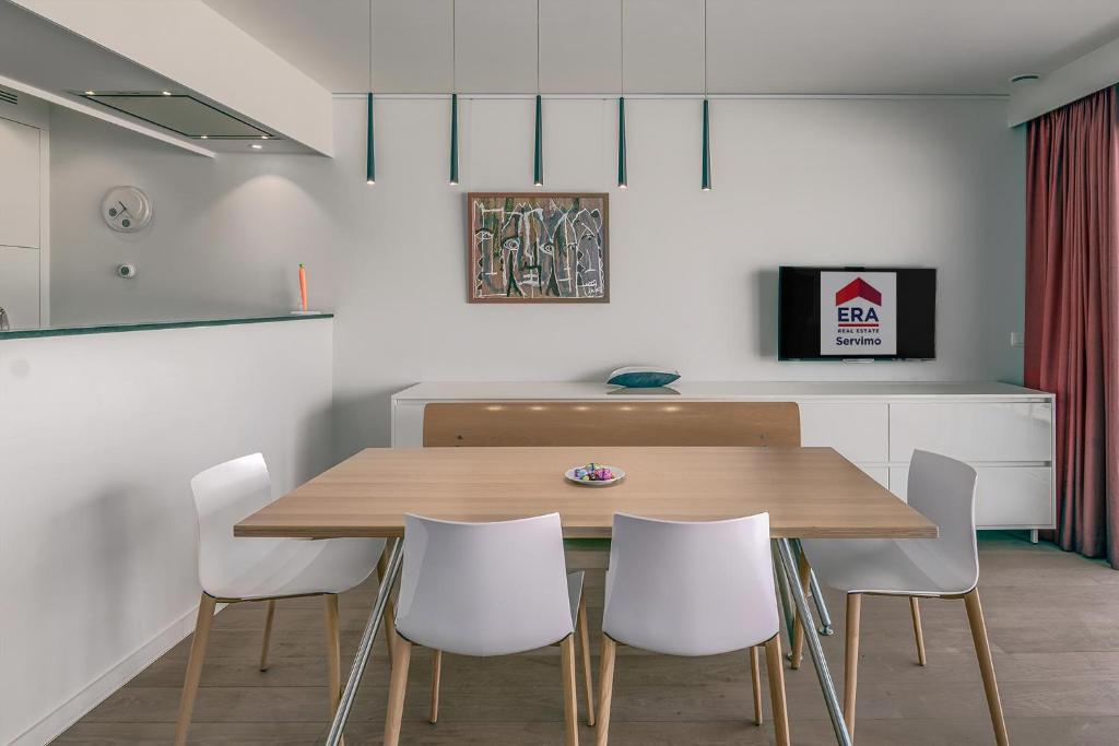 a dining room with a wooden table and white chairs at Sable Blanc 0201 in Sint-Idesbald