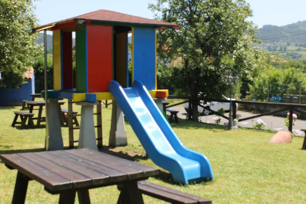 a playground with a slide and a wooden bench at Rodiles Rural Apartamentos in Selorio