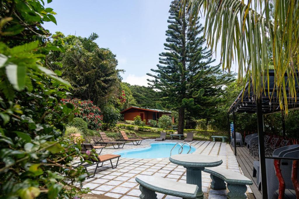 a patio with a table and chairs and a pool at Cabañas La Pradera in Monteverde Costa Rica