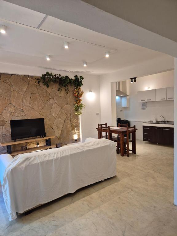 a living room with a white bed and a stone wall at Departamento Centrico SMA in San Martín de los Andes