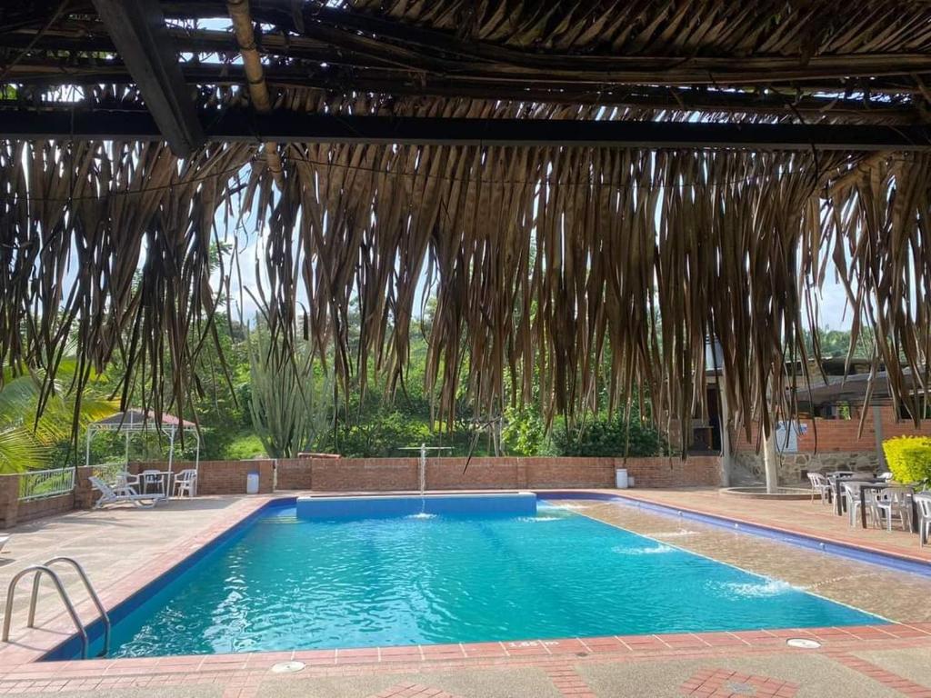 a large swimming pool with a large straw roof at LOMA LINDA Hotel de Naturaleza in La Mesa
