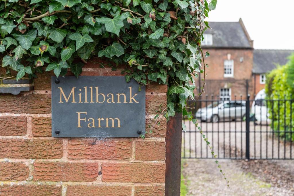 un panneau indiquant la ferme de millbank sur un mur de briques dans l'établissement Millbank Farm Cottage, à Stafford