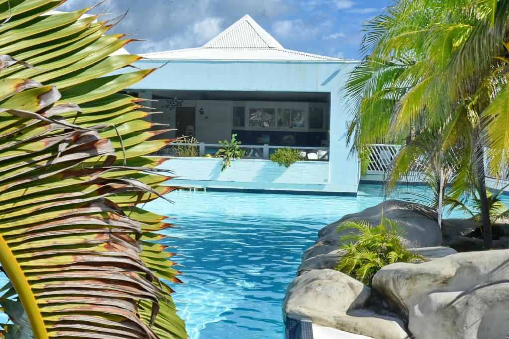 a swimming pool with palm trees and a house at Appartement Manganao beach in Saint-François