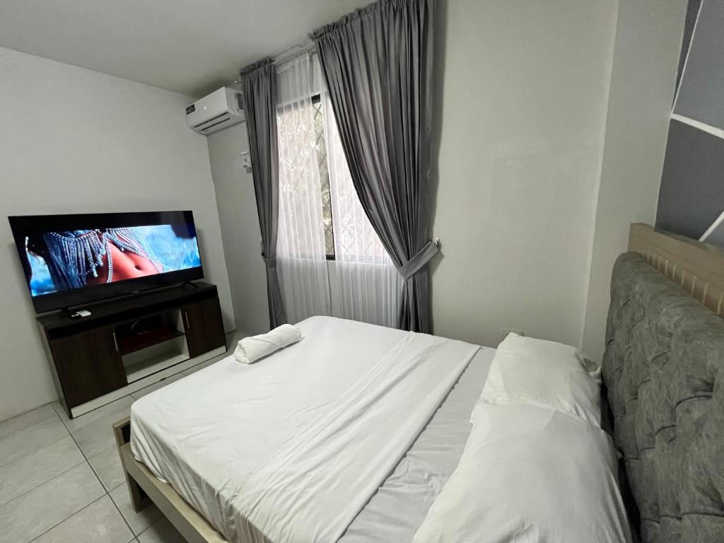 a bedroom with a bed and a flat screen tv at Enorme 3 habitaciones, 7 camas, centro de machala in Machala