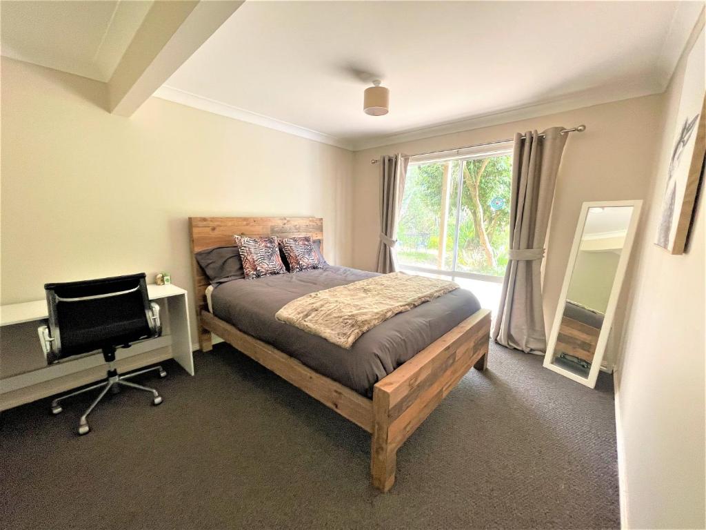 a bedroom with a bed and a desk and a television at Luxury Mountain Retreat with Gym, Heated Private Pool & Bush Views in Springwood