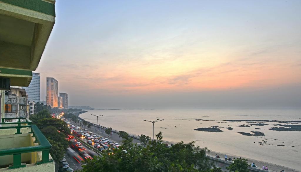 una strada trafficata con una folla di auto parcheggiate sulla spiaggia di Sea Green Hotel a Mumbai
