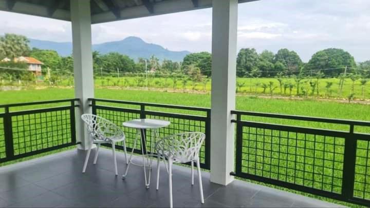 a porch with a table and chairs and a field at Baksaei Retreat Ricefield Villas in Kampot