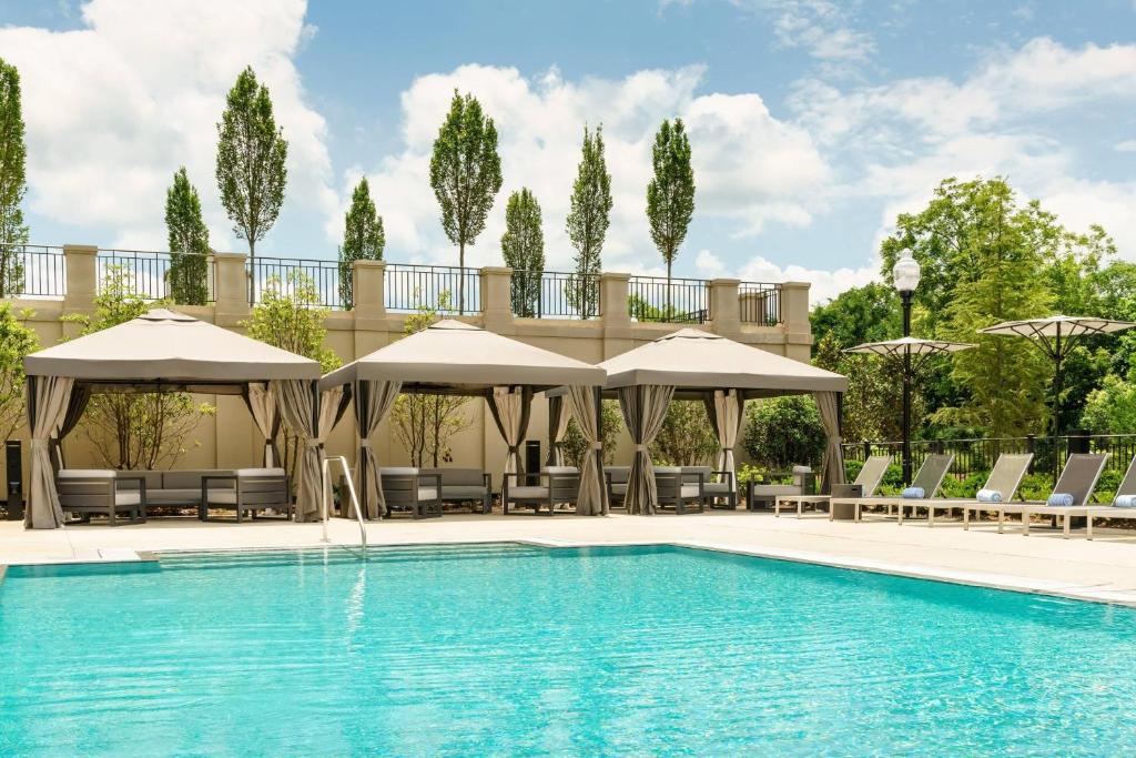 a swimming pool with chairs and umbrellas at AC Hotel by Marriott Spartanburg in Spartanburg