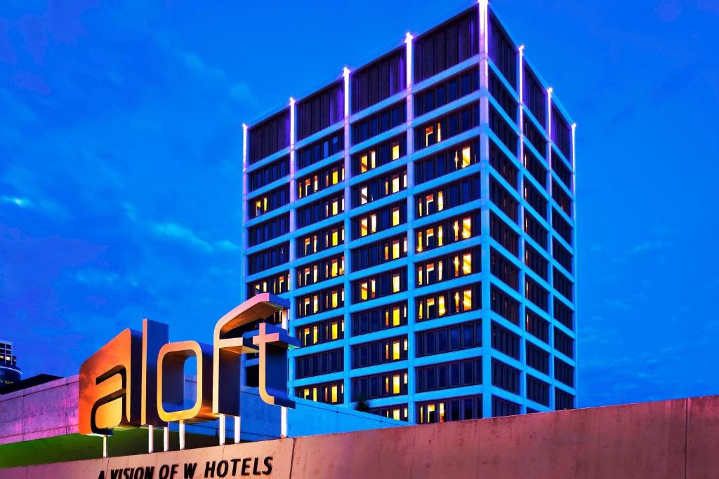Un edificio alto con un cartel delante. en Aloft Tulsa Downtown, en Tulsa