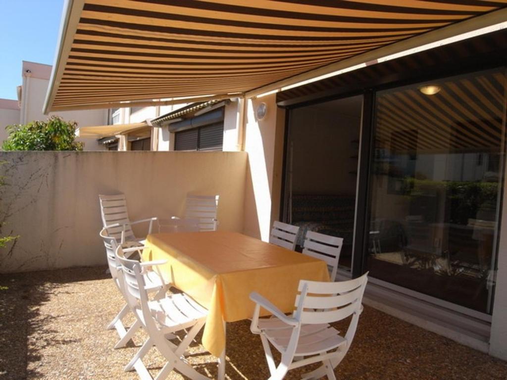 - une table et des chaises en bois sous un auvent sur une terrasse dans l'établissement Appartement 3 Pièces RDC, Piscine-Tennis, Parking à Argelès - FR-1-776-114, à Argelès-sur-Mer