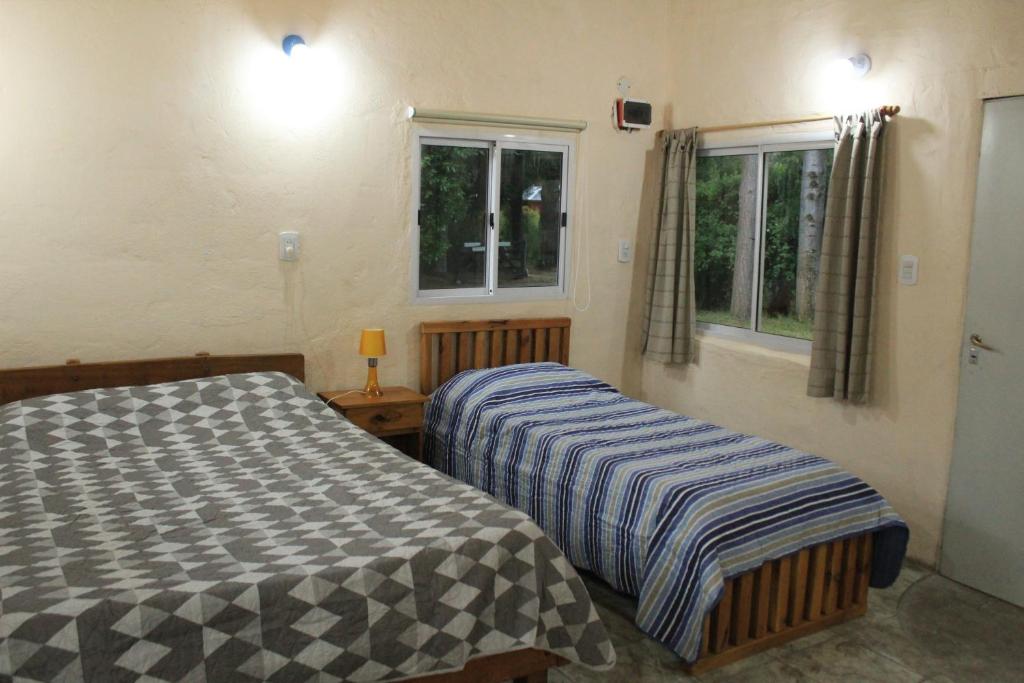 two beds in a room with two windows at Monoambiente Chacra Nadia in Epuyén