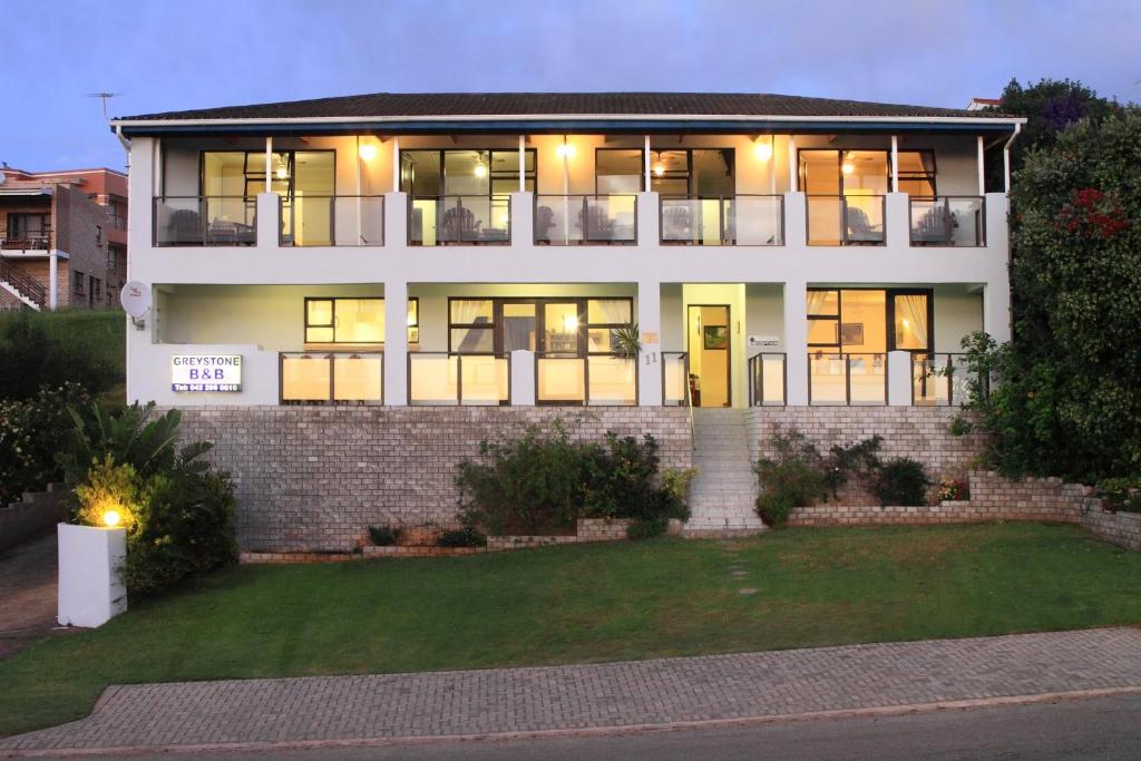 a large white house with its lights on at Greystone Guesthouse in Jeffreys Bay