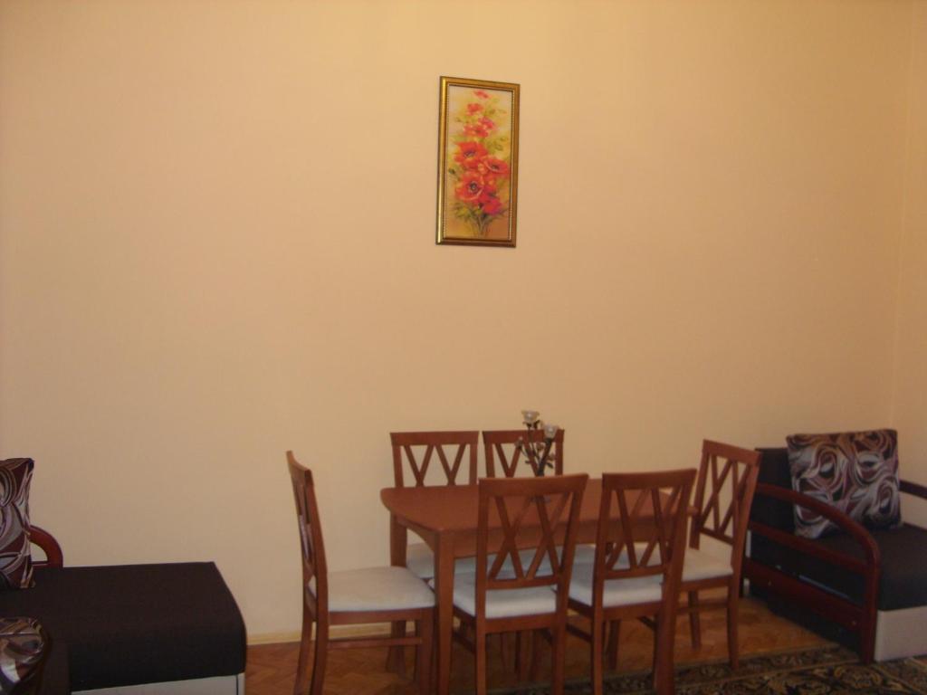 a dining room with a table and chairs and a painting on the wall at Apartment Viatores in Lviv