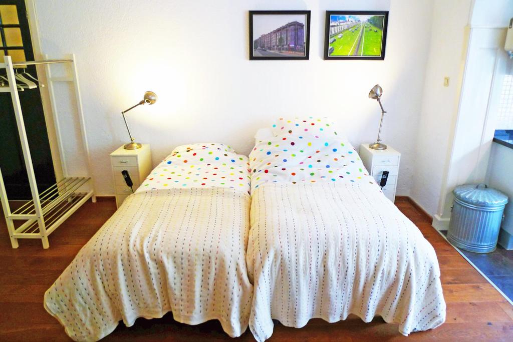 2 camas en un dormitorio con 2 lámparas en la pared en Bed & Breakfast Walenburg en Róterdam