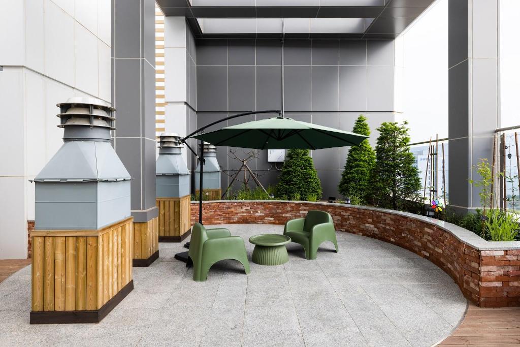 a patio with green chairs and an umbrella at Grand Bleu Hotel & Residence in Incheon