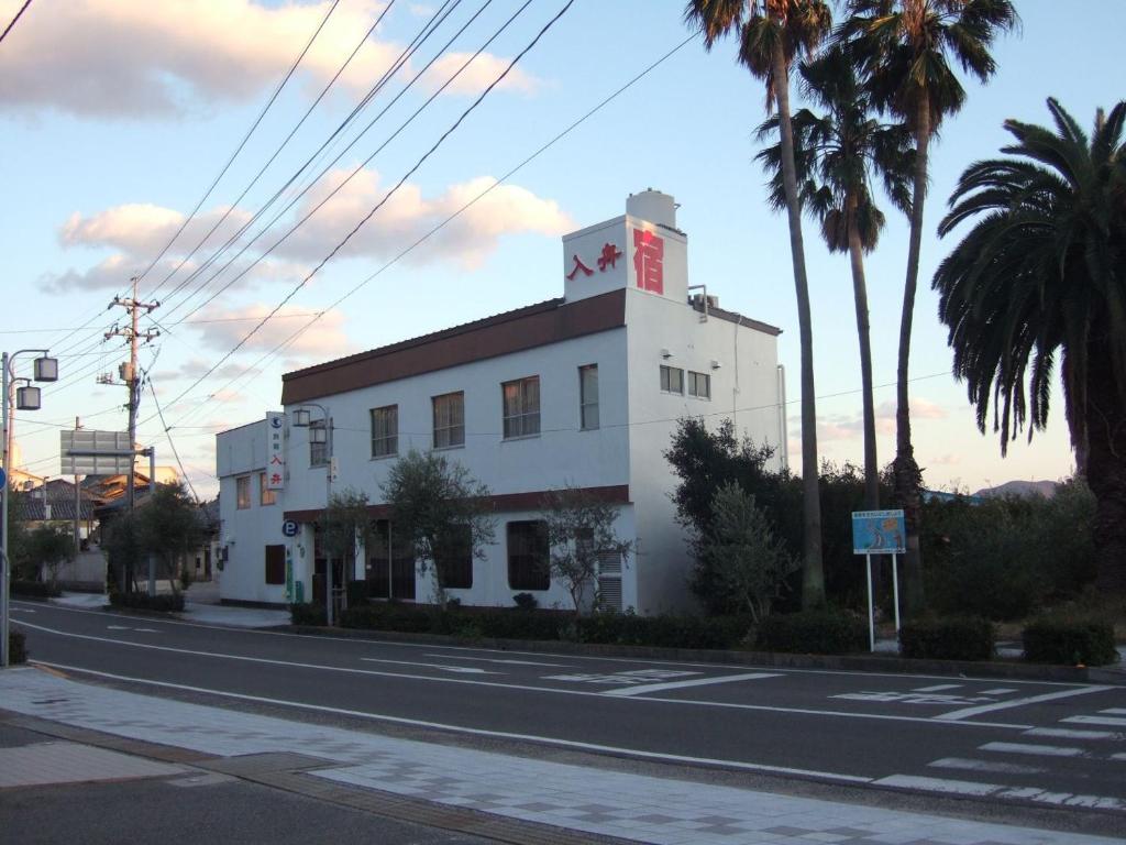 a white building on a street with palm trees at Irifune in Tonosho