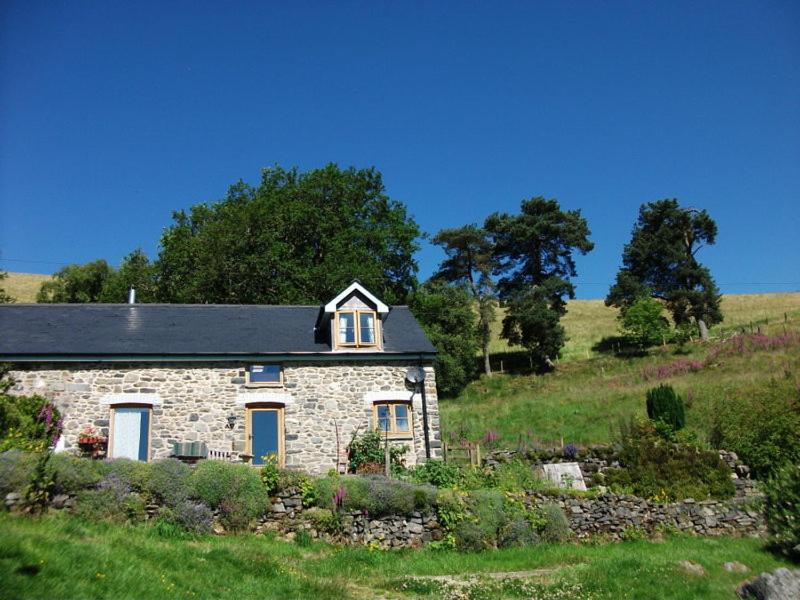een stenen huis in het midden van een veld bij Swallow Barn in Llanwrtyd Wells