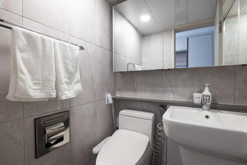 a bathroom with a toilet and a sink and a mirror at Grand Bleu Hotel & Residence in Incheon