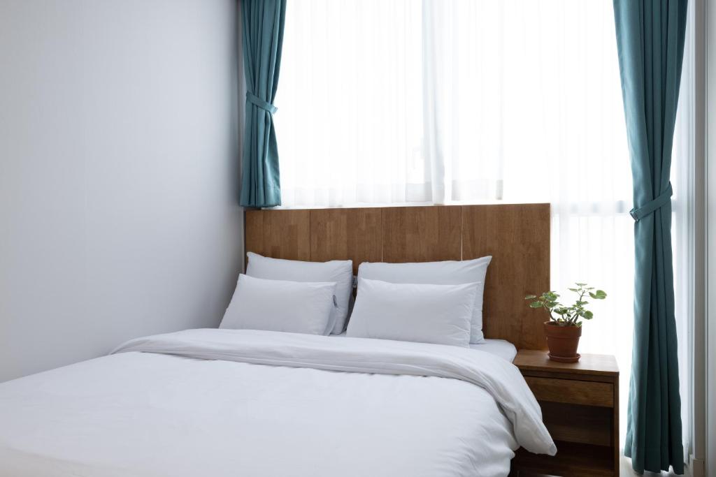 a bedroom with a bed with white sheets and a window at Grand Bleu Hotel & Residence in Incheon