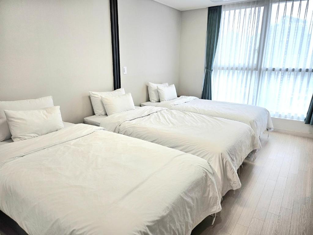 two beds in a hotel room with white sheets at Grand Bleu Hotel & Residence in Incheon