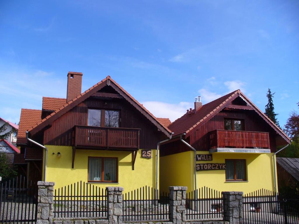 una casa amarilla con una valla delante de ella en Willa Storczyk en Szklarska Poręba