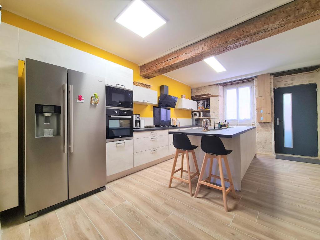 La cuisine est équipée d'un réfrigérateur en acier inoxydable et de deux tabourets de bar. dans l'établissement Maison Familiale du Quercy, à Montpezat-de-Quercy