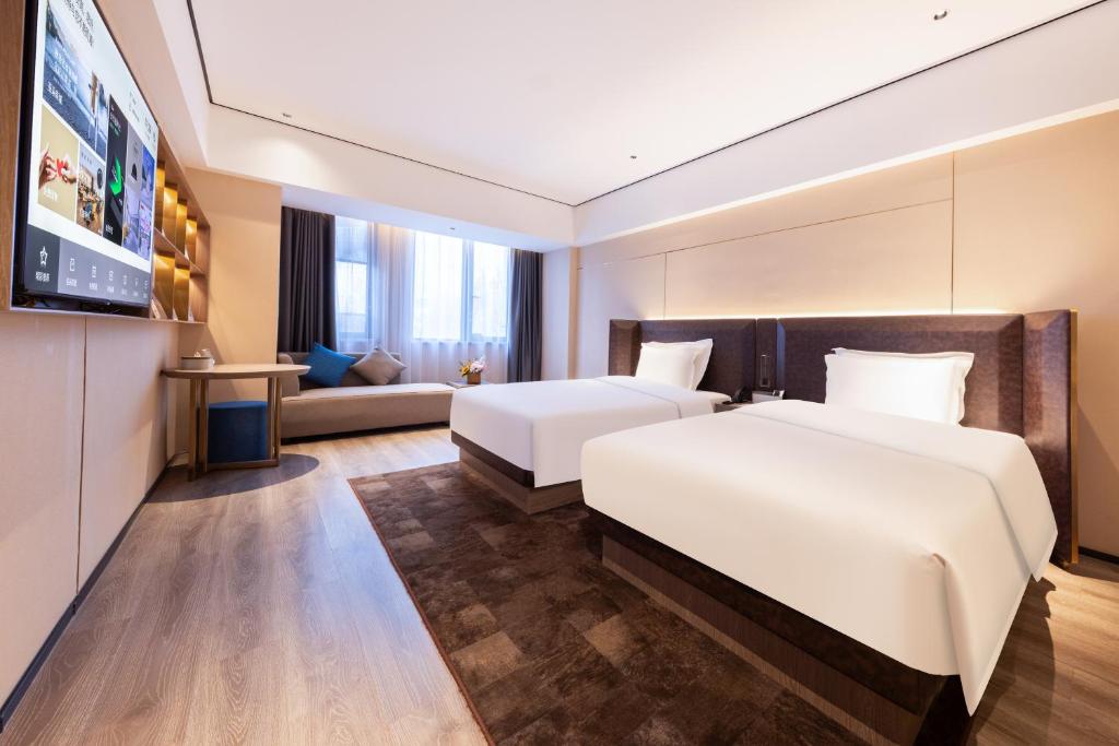 una camera d'albergo con due letti e un divano di Atour X Hotel Wuhan Railway Station West Square a Wuhan