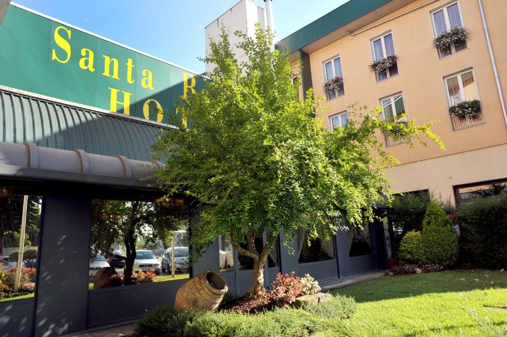 un albero di fronte a un edificio di Santa Barbara Hotel a San Donato Milanese