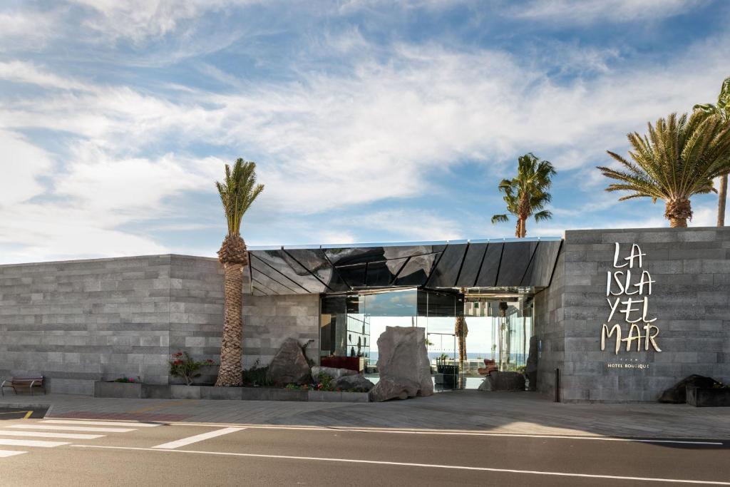 a building with palm trees in front of it at La Isla y el Mar, Hotel Boutique in Puerto del Carmen