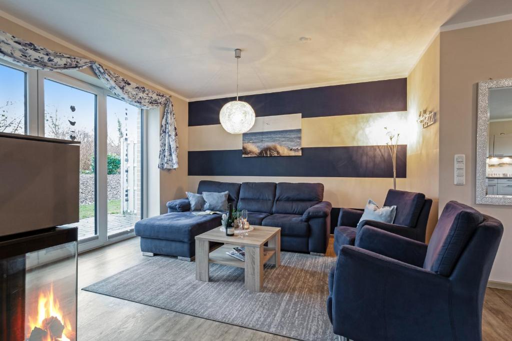 a living room with blue couches and a tv at Wellness - Ferienhaus Steilküste in Fehmarn