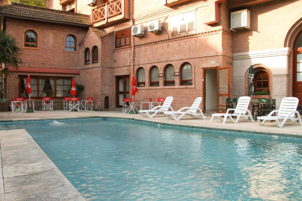 a swimming pool with lounge chairs and a building at Hotel Algeciras in Pinamar