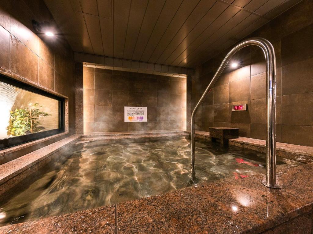 a bath tub with a shower in a building at SUPER HOTEL Ikebukuro West Natural Hot Spring in Tokyo