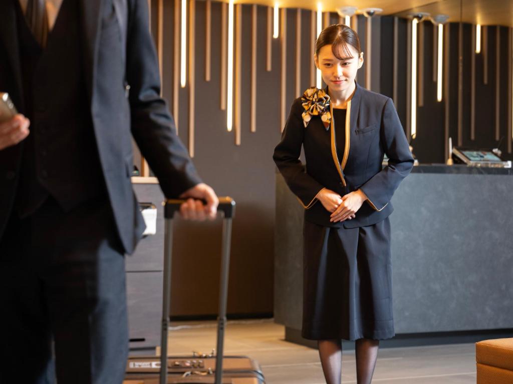 a woman in a suit standing next to a man at SUPER HOTEL Ikebukuro West Natural Hot Spring in Tokyo