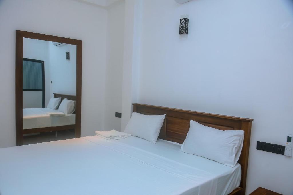 a bedroom with a large white bed with a mirror at Mirissa Breeze in Mirissa