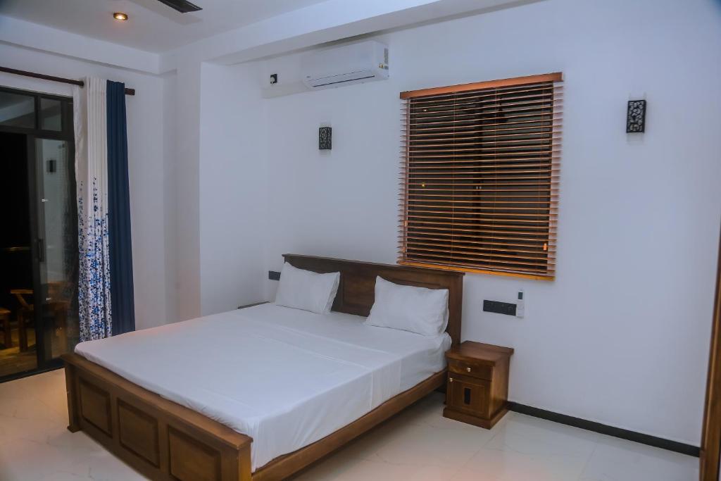 a white bedroom with a bed and a window at Mirissa Breeze in Mirissa