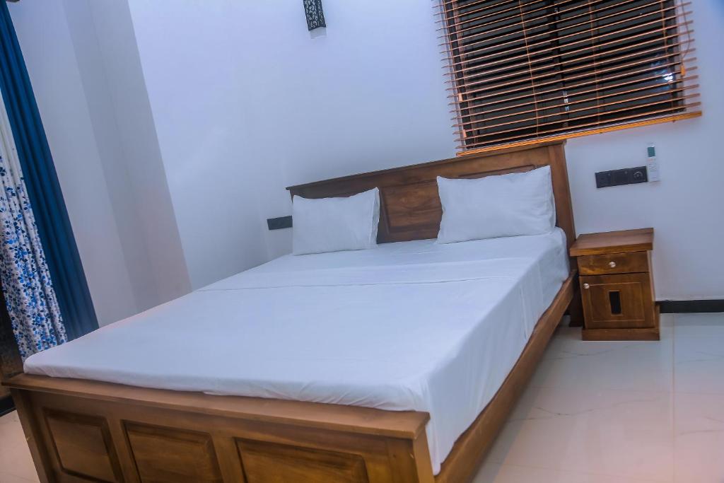 a bedroom with a bed with a wooden headboard at Mirissa Breeze in Mirissa