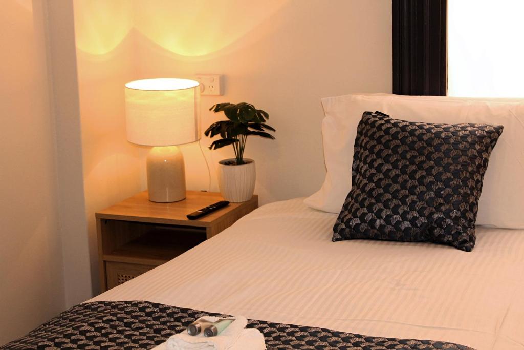 a bedroom with a bed with a lamp and a plant at The Hampden Suites in Wagga Wagga