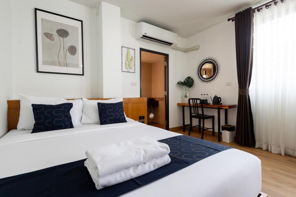 a bedroom with a large white bed with blue pillows at Nature Boutique Hotel Ratchayothin in Bangkok